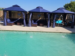 A poolside area with three covered seating areas, each with a bench and a table. - EL Dorado ranch resort (Crystal City)