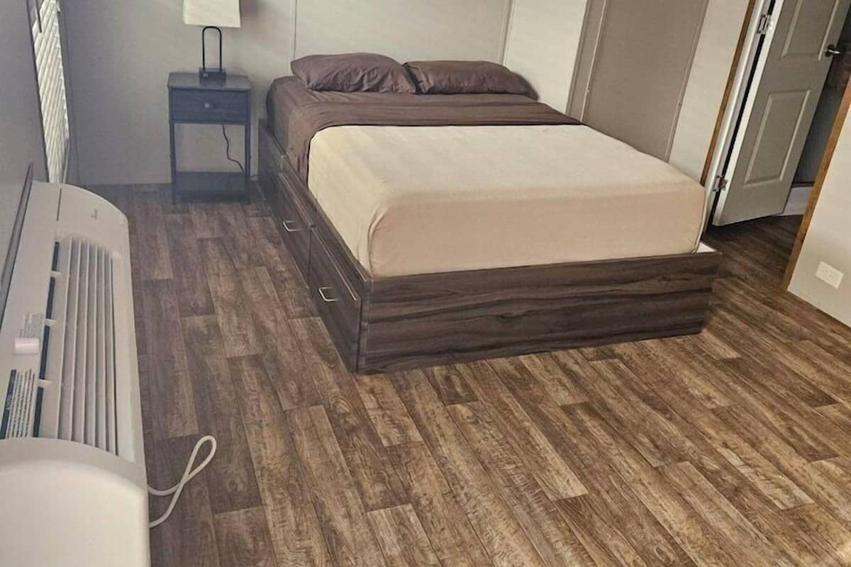 A bedroom with a bed, a nightstand, a lamp, and a radiator.