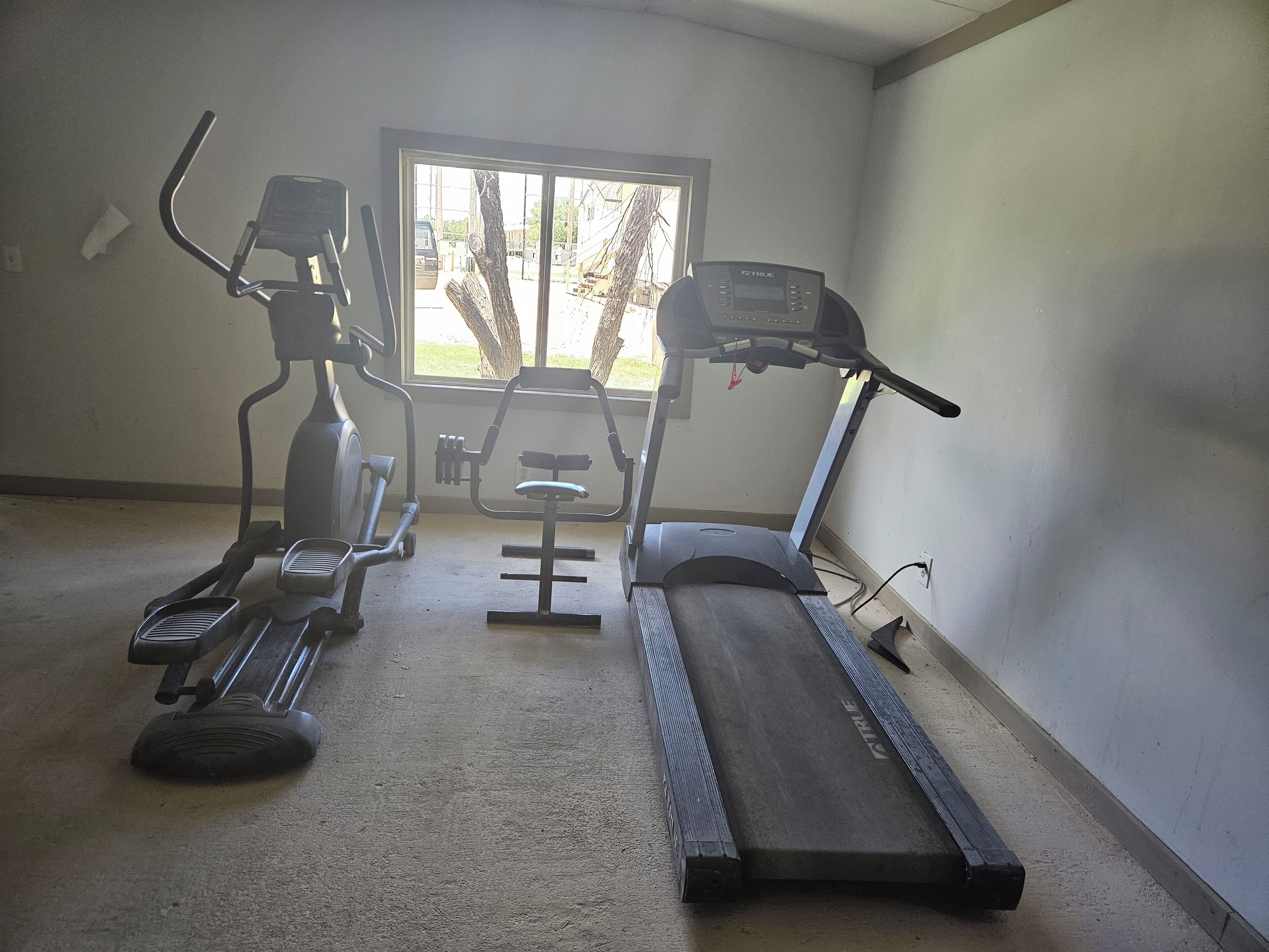 A gym with an elliptical, a stationary bike, and a treadmill.
