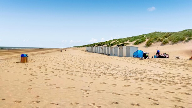 En strand med mobile toiletter, en skraldespand og et telt.