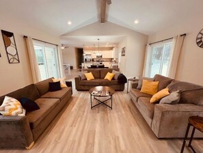 Relax in this spacious living area with a central coffee table surrounded by comfortable sofas and a high ceiling with exposed beams.