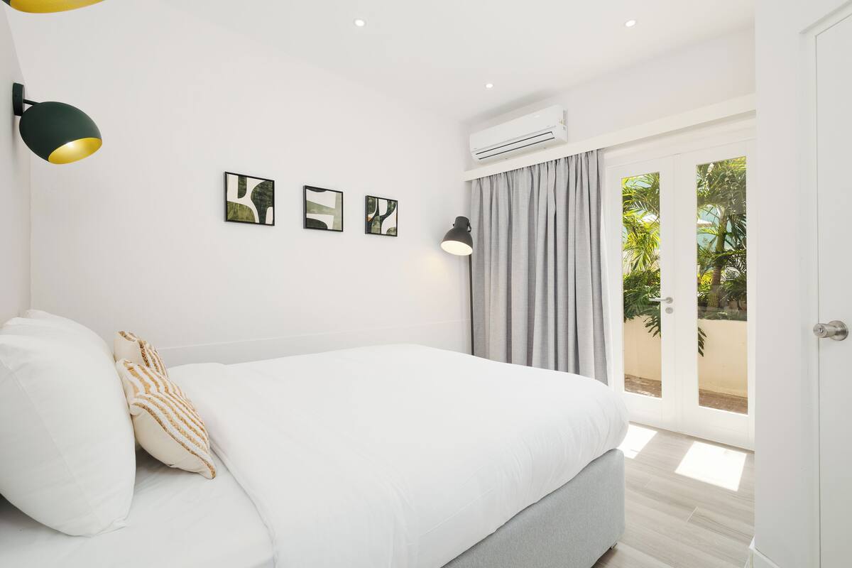 A bedroom with a bed, a wall-mounted lamp, and an air conditioning unit.