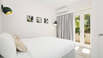 A bedroom with a bed, a wall-mounted lamp, and an air conditioning unit.