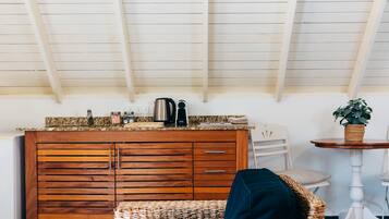 A kitchen with wooden cabinets, a coffee maker, and a plant on a small table.