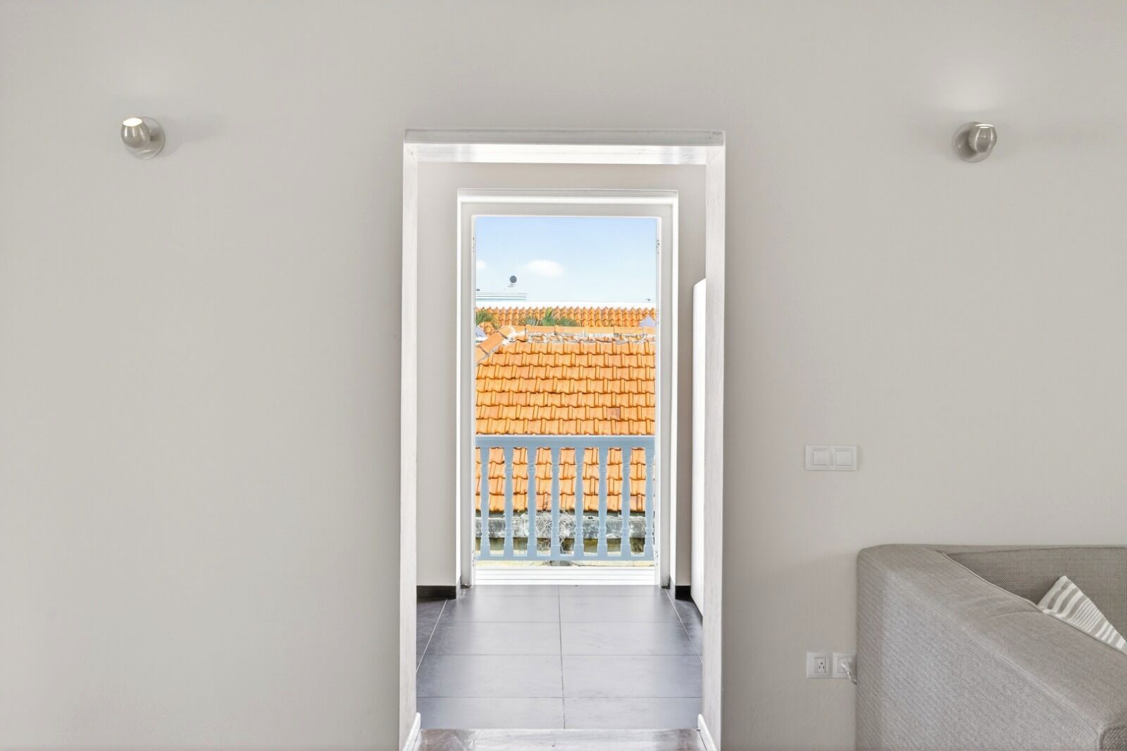Un couloir menant à un balcon doté d’un toit en tuiles et d’une balustrade.