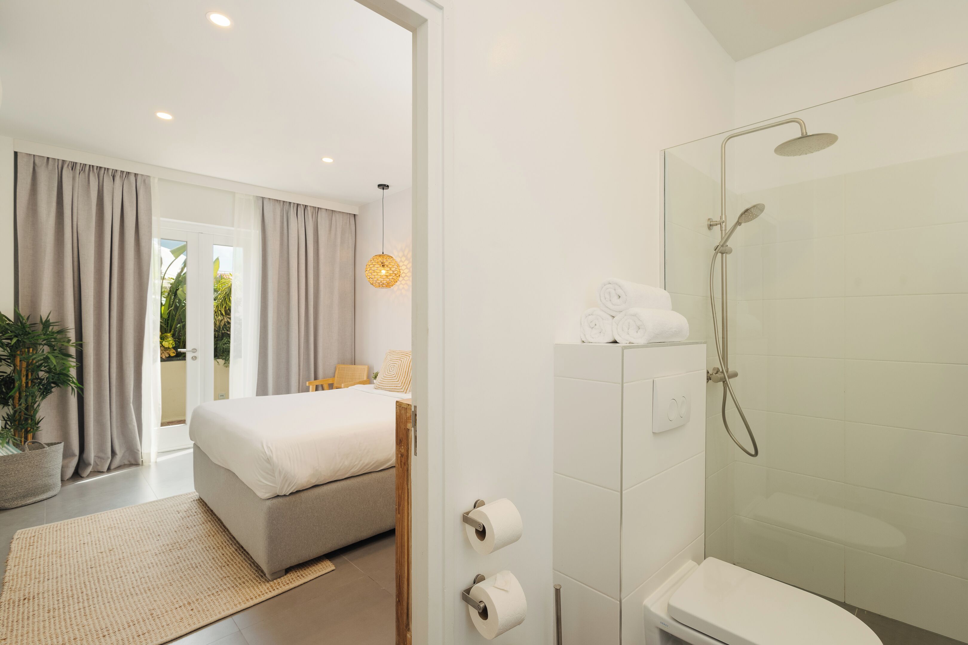 Ein modernes Hotelzimmer mit Bett, Dusche und Blick ins Freie.