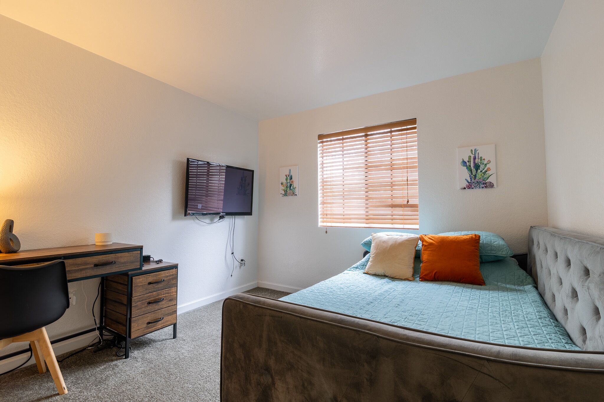 A bedroom with a bed, a desk, and a television.