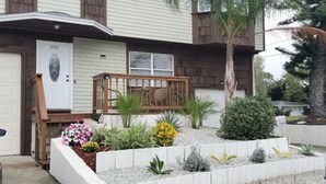 Una casa residenziale con portico, cassetta delle lettere e un giardino curato con diverse piante e fiori.