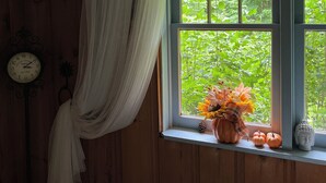 Une pièce avec une fenêtre, une horloge et un vase rempli de fleurs.