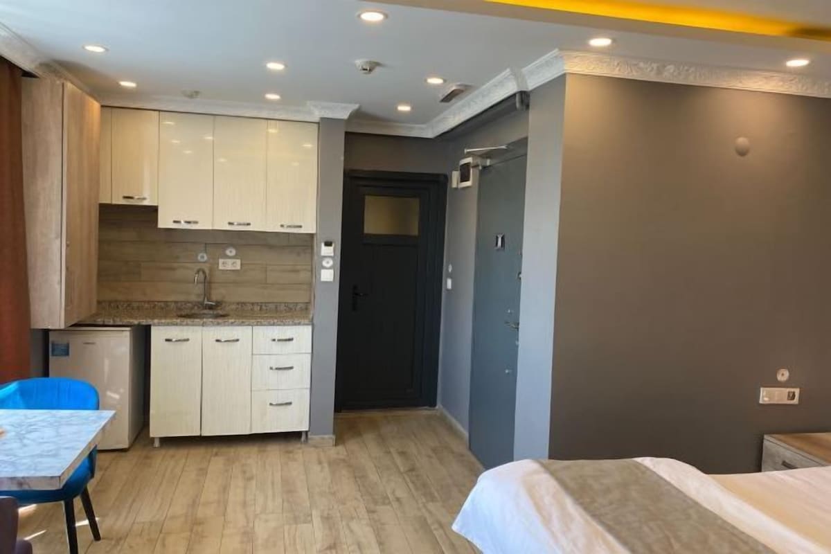 Een compacte hotelkamer met kitchenette, een bed en een kleine tafel.