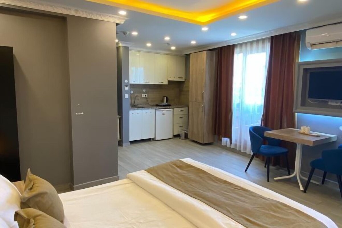 Une chambre d’hôtel comprenant un lit, une petite kitchenette, un coin repas avec des chaises et un téléviseur fixé au mur.