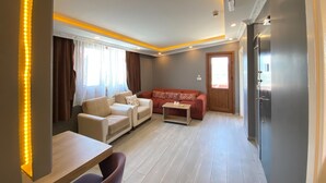 A modern living room with a sofa, chairs, a small table, and a refrigerator. - Sahrakent Otel Kadıköy  (Istanbul)