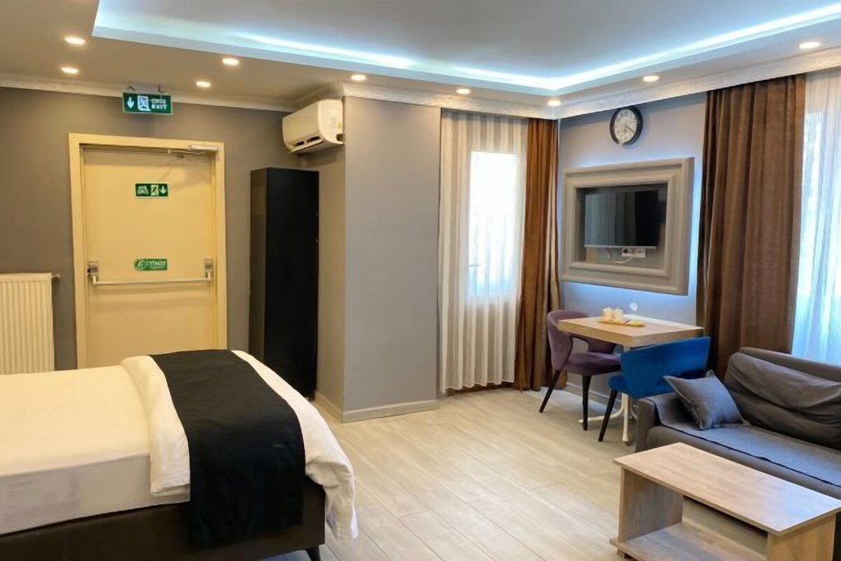 Une chambre d’hôtel avec un lit, un bureau, un canapé et une télévision.