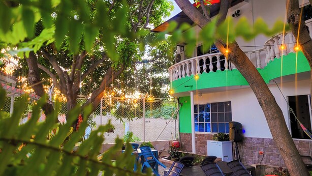 Una casa con balcón, un pequeño jardín y luces colgantes.