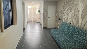 Un pasillo con sofá, piso de baldosas y una puerta al final.