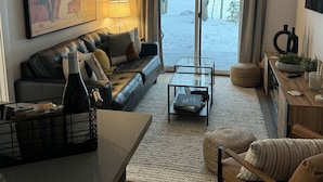 Una sala de estar moderna con un sofá de cuero, una mesa de centro de vidrio y una zona de comedor con una mesa y sillas de madera.