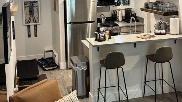 Una cocina moderna con una isla central, electrodomésticos de acero inoxidable y taburetes de bar.