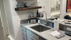 Una cocina moderna con lavavajillas integrado, un lavamanos y una encimera con hervidor y tazas.