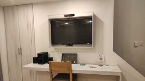 Un espacio de oficina pequeño y privado, con un escritorio, una silla, un televisor montado en la pared y un armario.