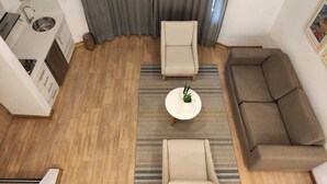 Una sala de estar moderna con un sofá, una silla, una mesita de centro y un área de cocina con un lavaplatos y una estufa.