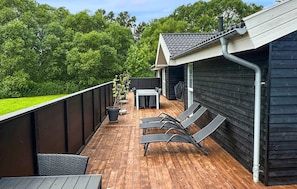 A wooden deck with a table and chairs, a grill, and a covered area.
