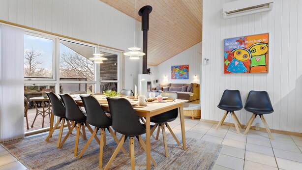 Een moderne eetruimte met een houten tafel, zwarte stoelen en een groot raam.