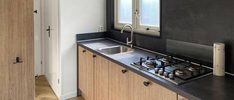 A modern kitchen with a stainless steel sink, a gas stove, and wooden cabinets.