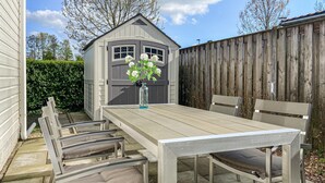 A patio with a wooden table and chairs, a small shed, and a wooden fence. - Gorgeous home in Heinkenszand with WiFi (Heinkenszand)