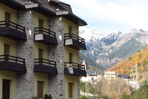 A multi-story building with stone facade and balconies, set against a mountainous backdrop. - Snö Bielsa (Bielsa)