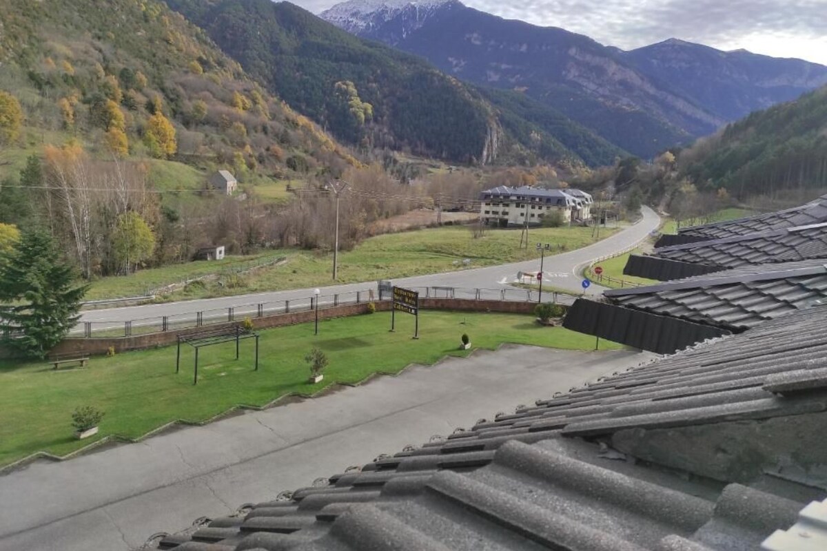 A view of a mountainous landscape with a road leading to a building with a sloped roof.