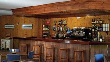 A bar area with wooden paneling, a pool table, and bar stools.