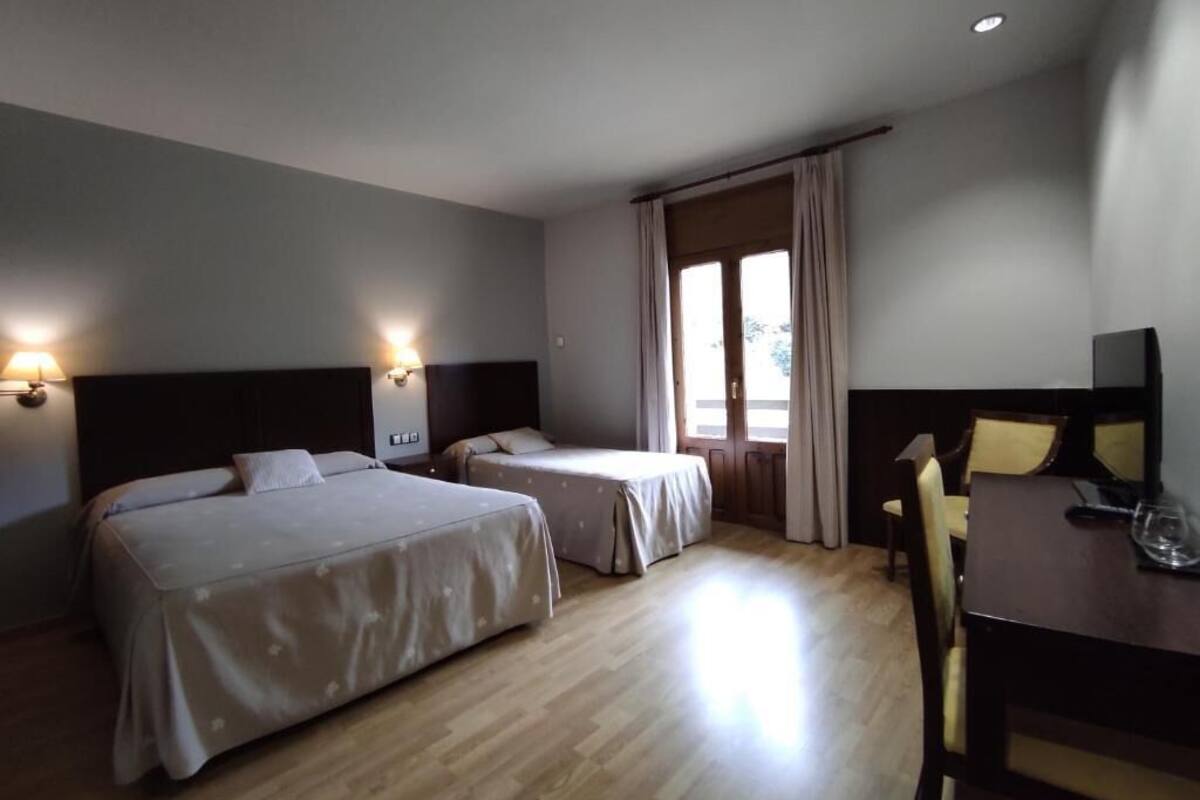 A hotel room with two beds, a desk, and a chair.