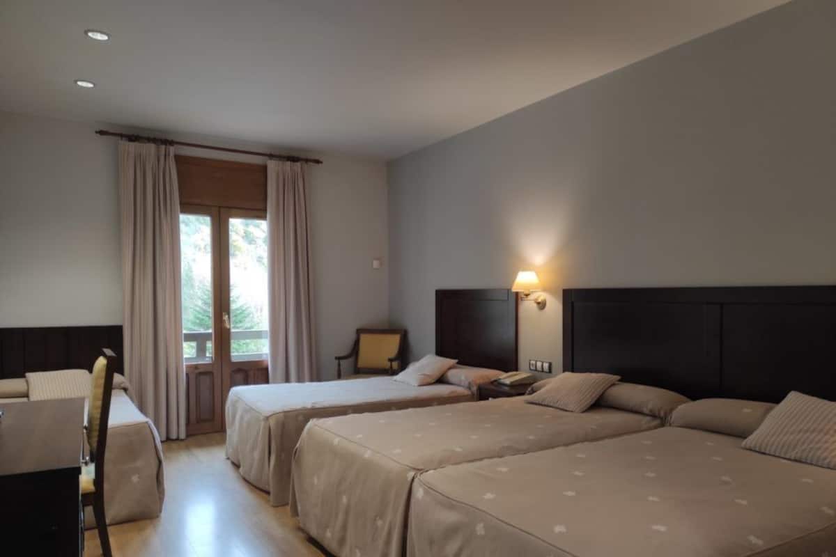 A hotel room with two beds, a desk, and a chair.