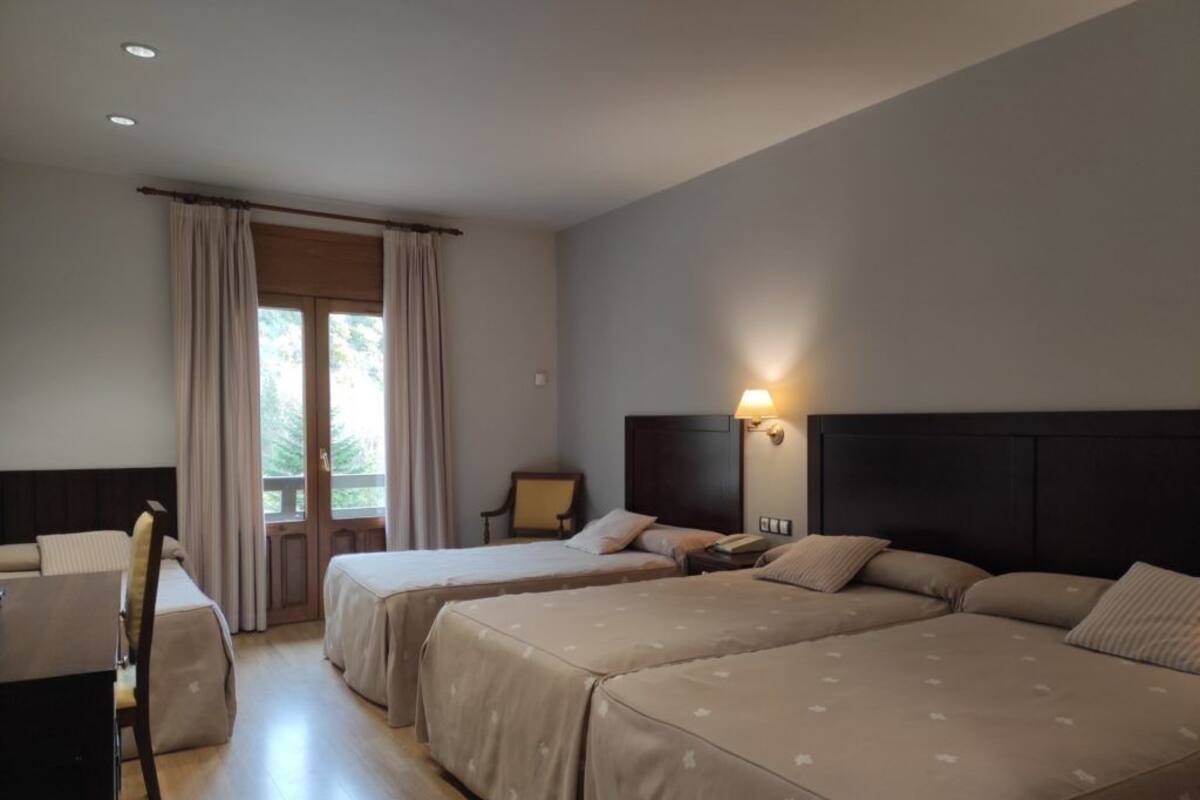 Une chambre d’hôtel avec deux lits, un bureau et une chaise.