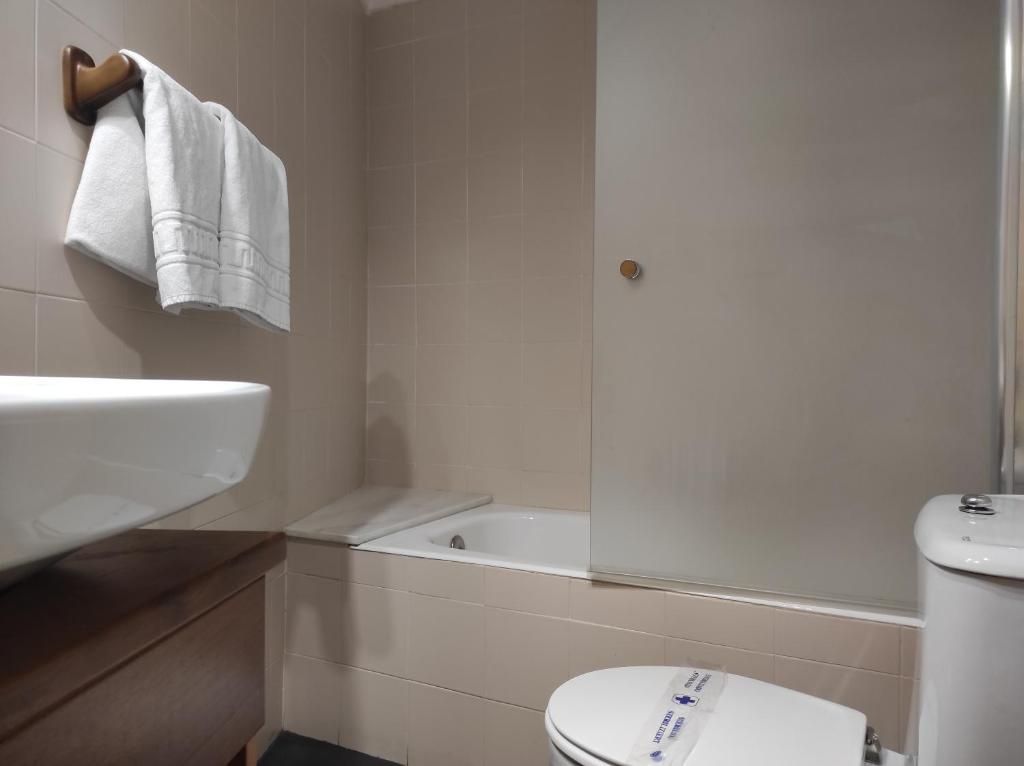 Een badkamer met een wit wastafel, een bad en een toilet.