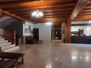 Um hall espaçoso com escada de madeira, balcão de recepção e sofá de couro.