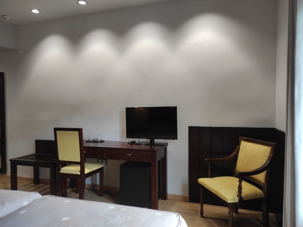 Une chambre d’hôtel équipée d’un lit, d’un bureau, d’une chaise, d’une télévision et d’une petite poubelle.