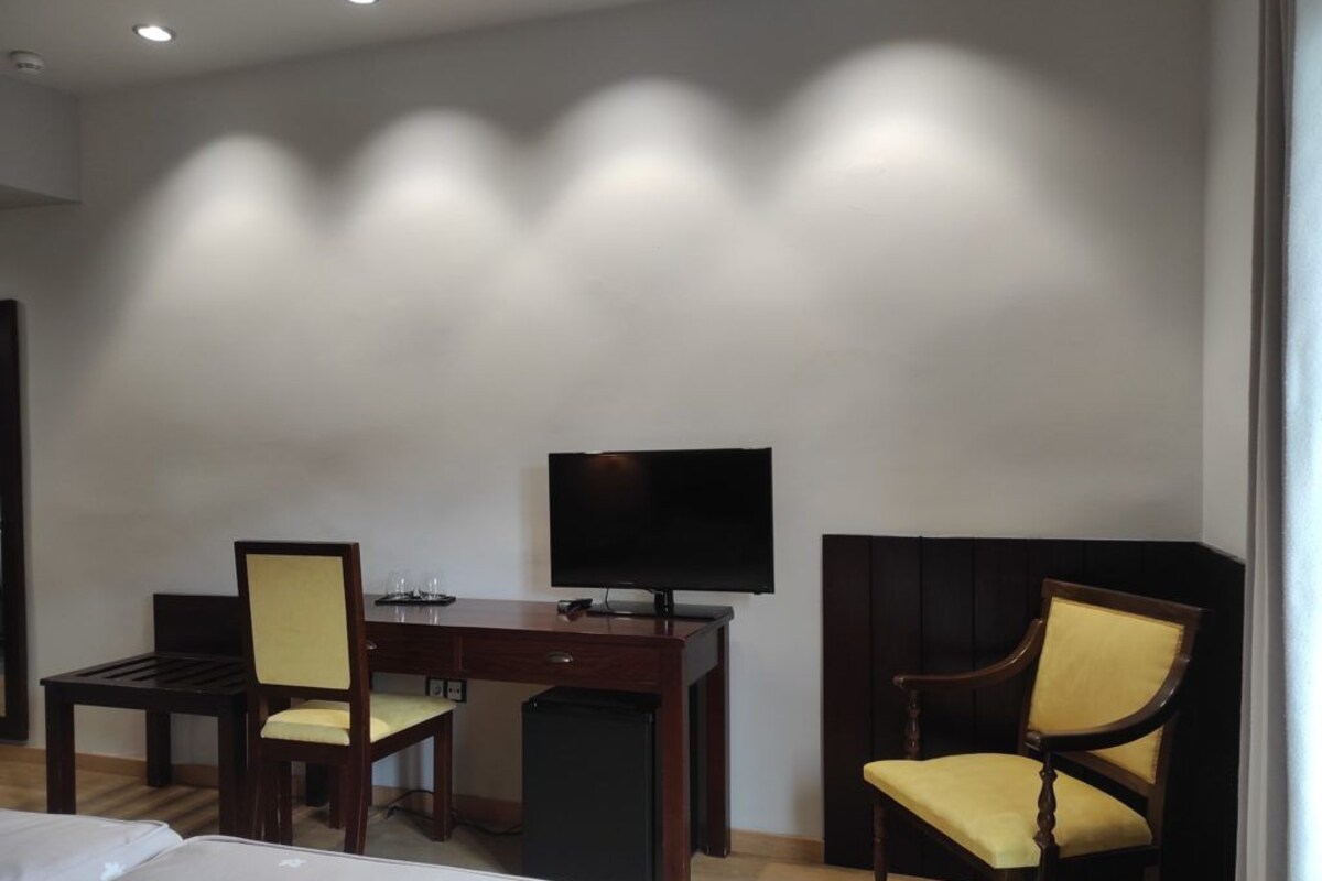 Una camera d'albergo con un letto, una scrivania, una sedia, una televisione e un piccolo cestino.