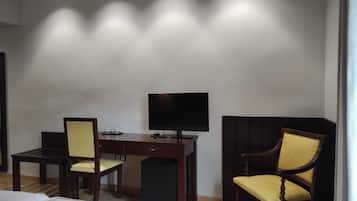 Une chambre d’hôtel équipée d’un lit, d’un bureau, d’une chaise, d’une télévision et d’une petite poubelle.