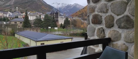 Een stenen muur met een balkon met uitzicht op een stad met gebouwen en bergen op de achtergrond.