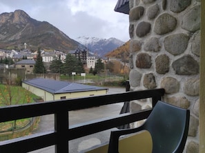 A stone wall with a balcony overlooking a town with buildings and mountains in the background. - Snö Bielsa (Bielsa)