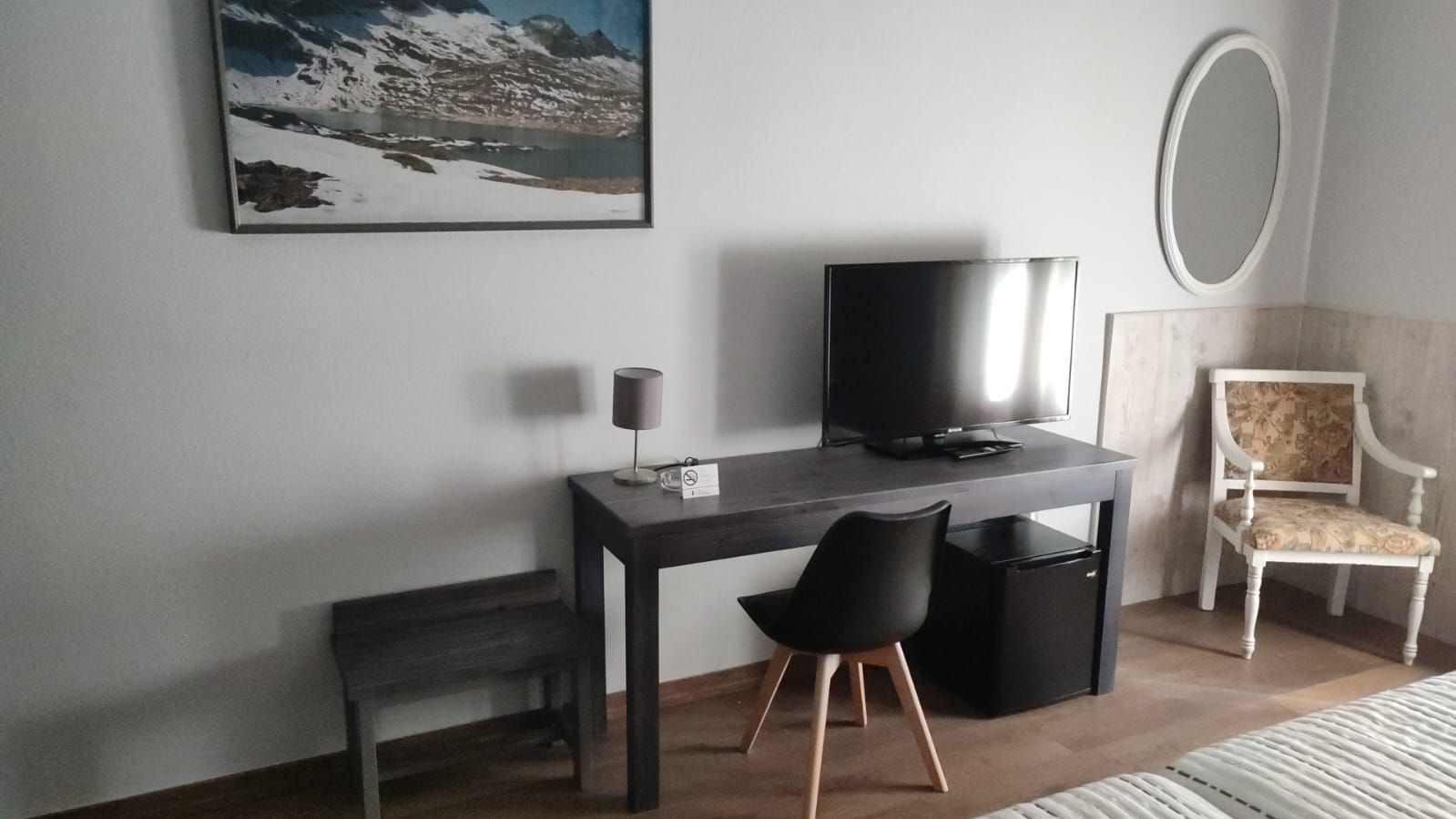 A modern room with a desk, a chair, a television, and a painting on the wall.