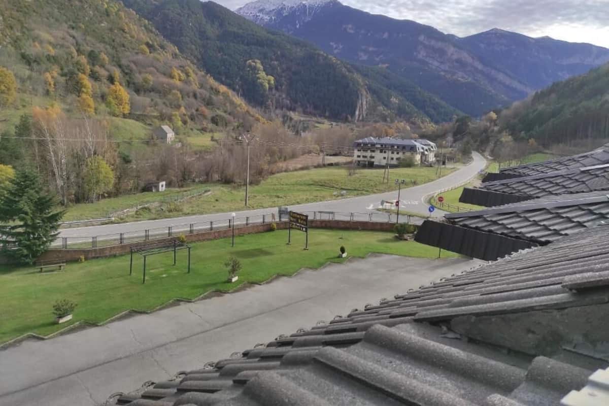 A view of a mountainous landscape with a road leading to a building with a sloped roof.