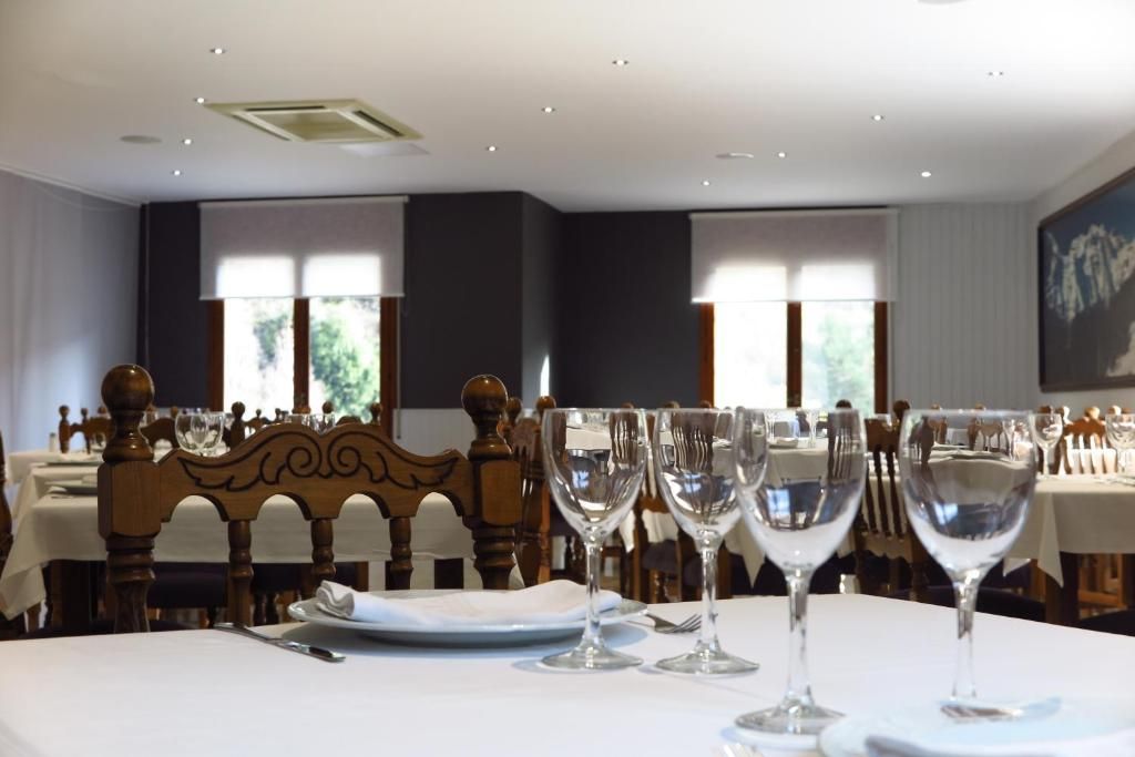 A dining area with tables set for a meal, featuring wooden chairs and clear glassware.