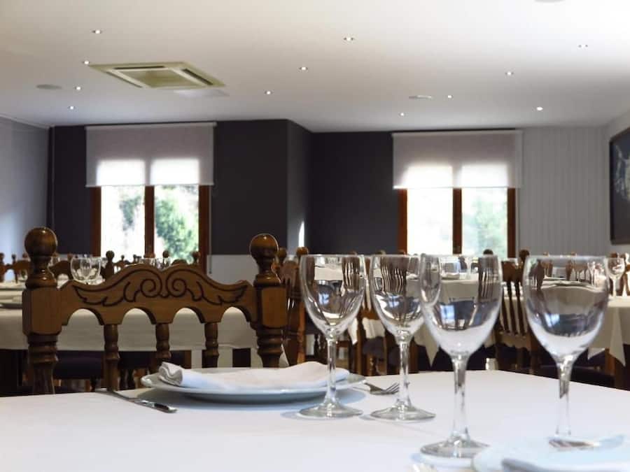 Un comedor con mesas dispuestas para una comida, con sillas de madera y vasos transparentes.