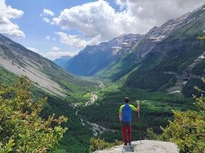 A person standing on a rocky outcrop overlooking a valley with a river, surrounded by mountains. - Snö Bielsa (Bielsa)