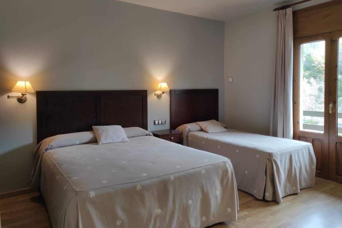 A hotel room with two beds, each with a headboard and bedside lamps.
