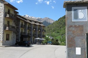 A hotel with stone facade, multiple balconies, and a mountain backdrop. - Snö Bielsa (Bielsa)