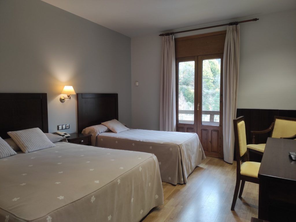 Habitación de hotel con dos camas, un escritorio y una silla.