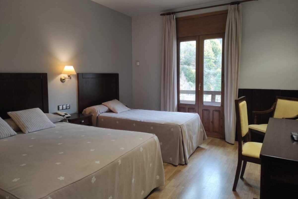 A hotel room with two beds, a desk, and a chair.